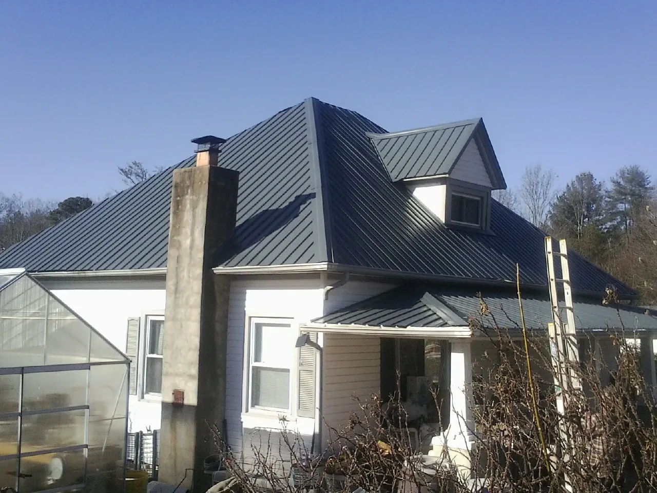 Dark blue standing seam metal roof on a white farmhouse with dormer — Slate & Tile Roof Repair by Roofing Brothers in Chanhassen