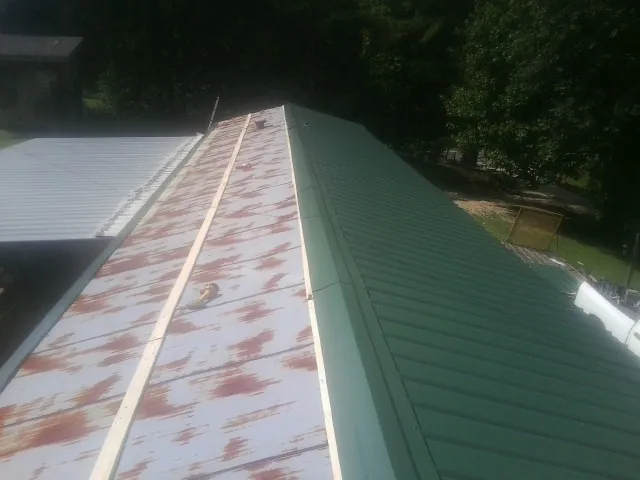 Old rusted panels beside newly installed green metal roofing — Wind Damage Roof Repair by Roofing Brothers in Chanhassen