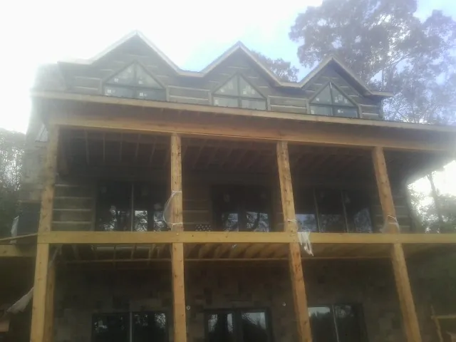 Dormers and porch framing on a large log home under construction — Roof Coating work by our crew in Chanhassen