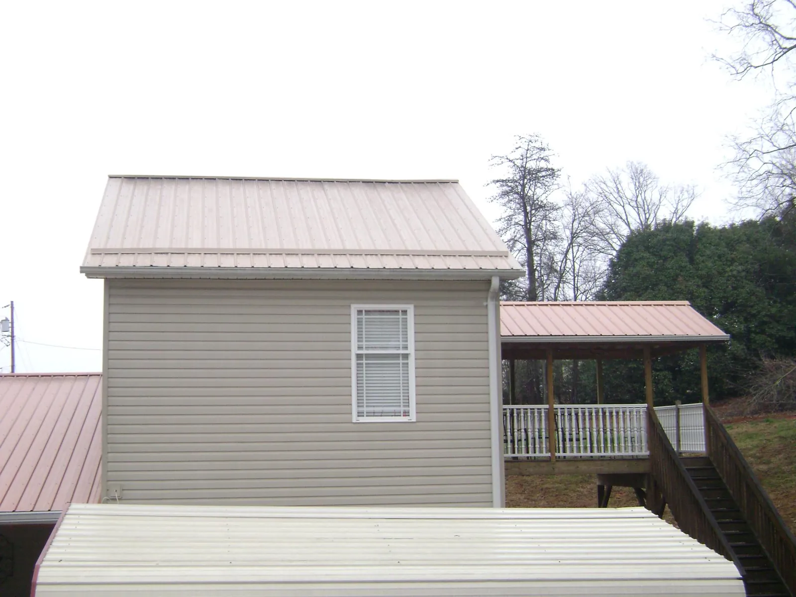 Tan metal roofs on a two story addition and attached porch, from a Roof Replacement job in Chanhassen