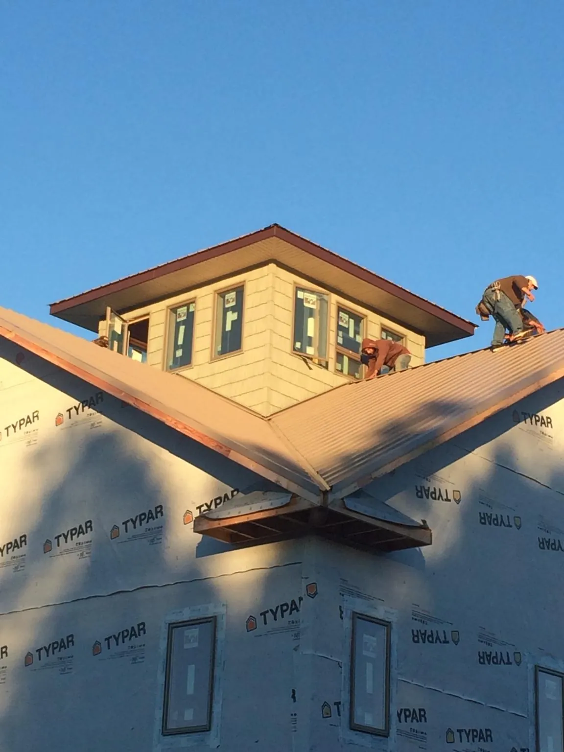 Roofers working around a rooftop cupola on a new metal roof at sunset — Roof Waterproofing in Chanhassen by Roofing Brothers